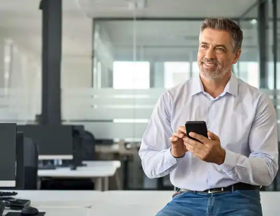 Happy Mid Aged Business Man Using Phone In Office