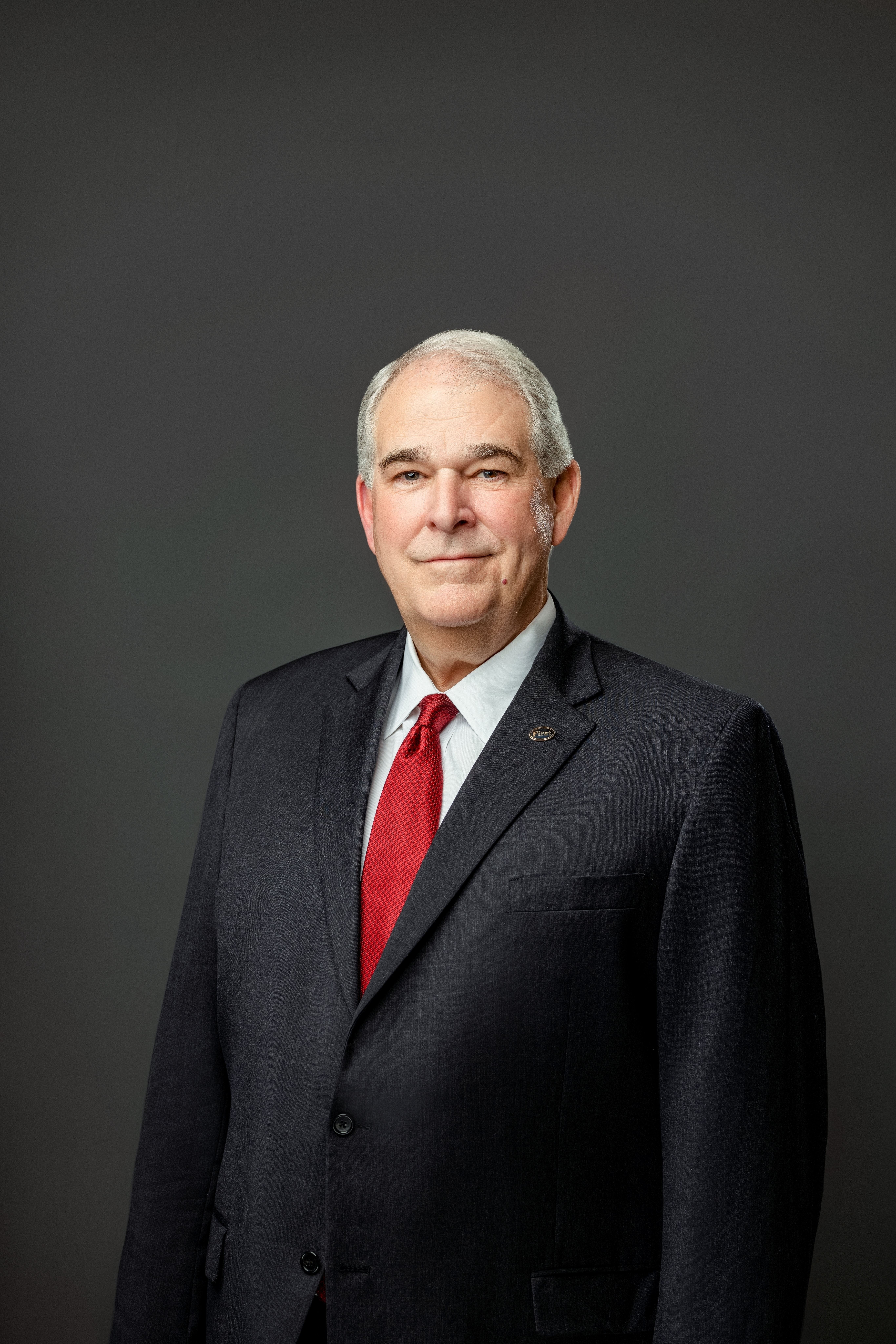 William H. Hayter in dark black suit with red tie