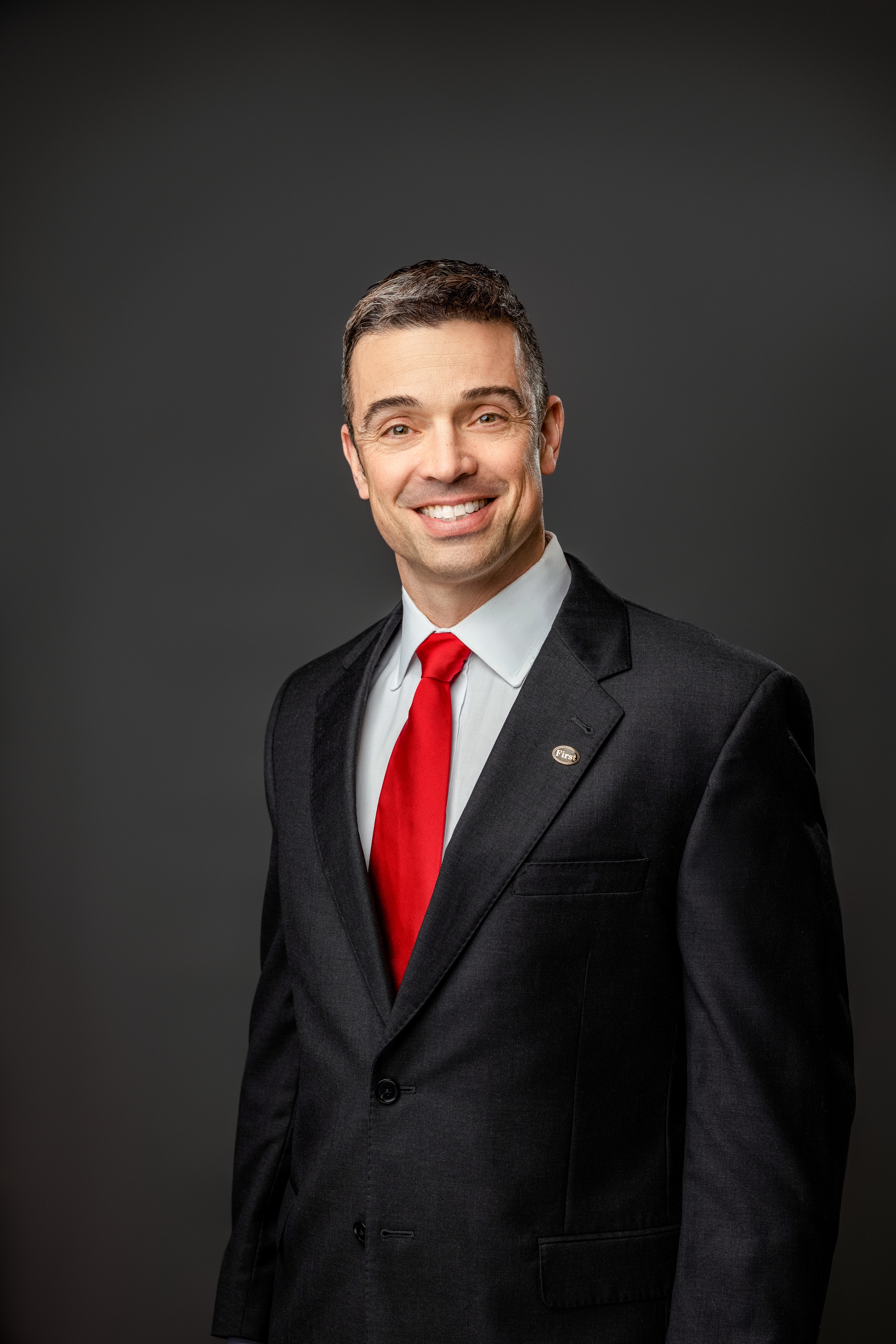 David A. Leonard, II in a black suit with red tie
