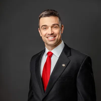 David A. Leonard, II in a black suit with red tie