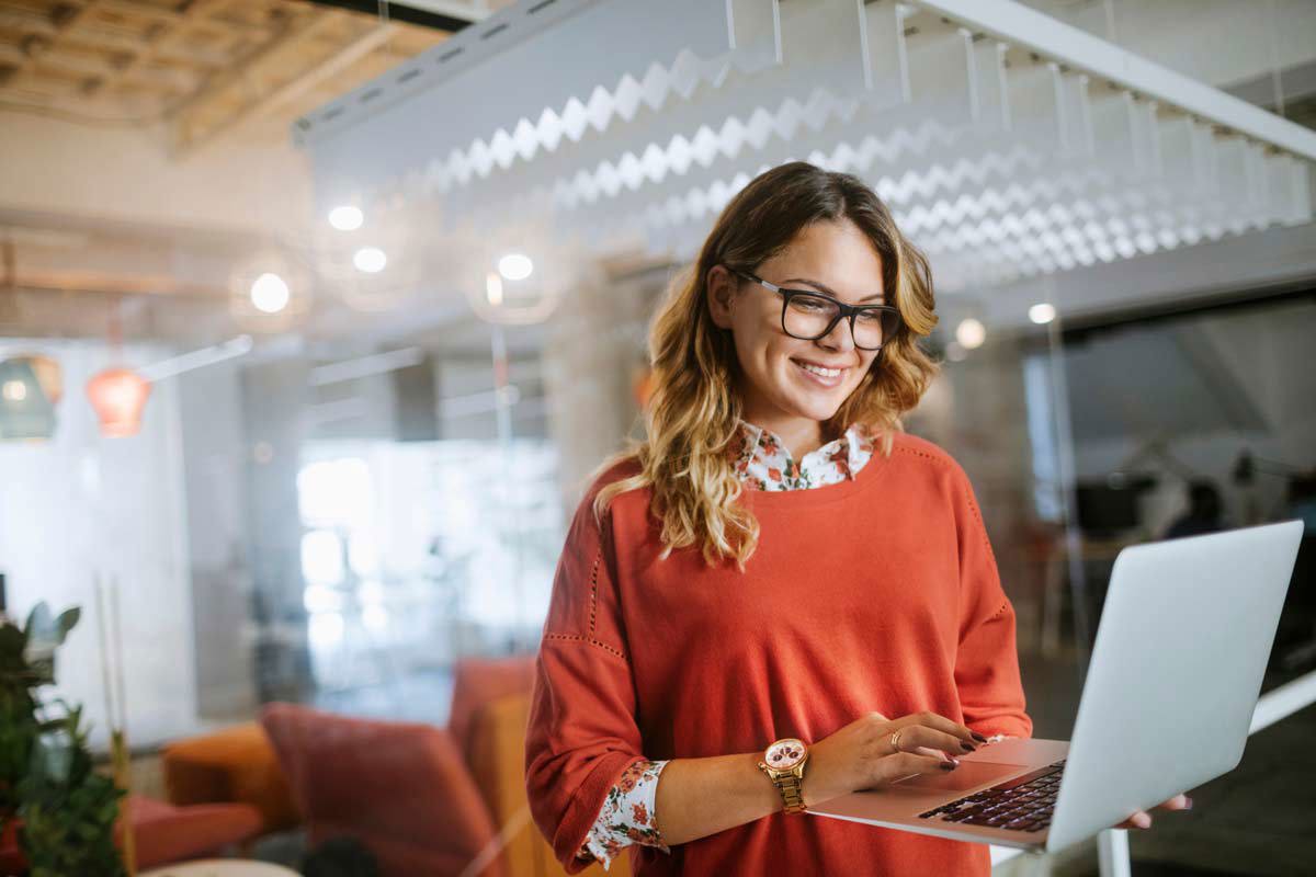 woman in glasses holding a laptop in the lobby