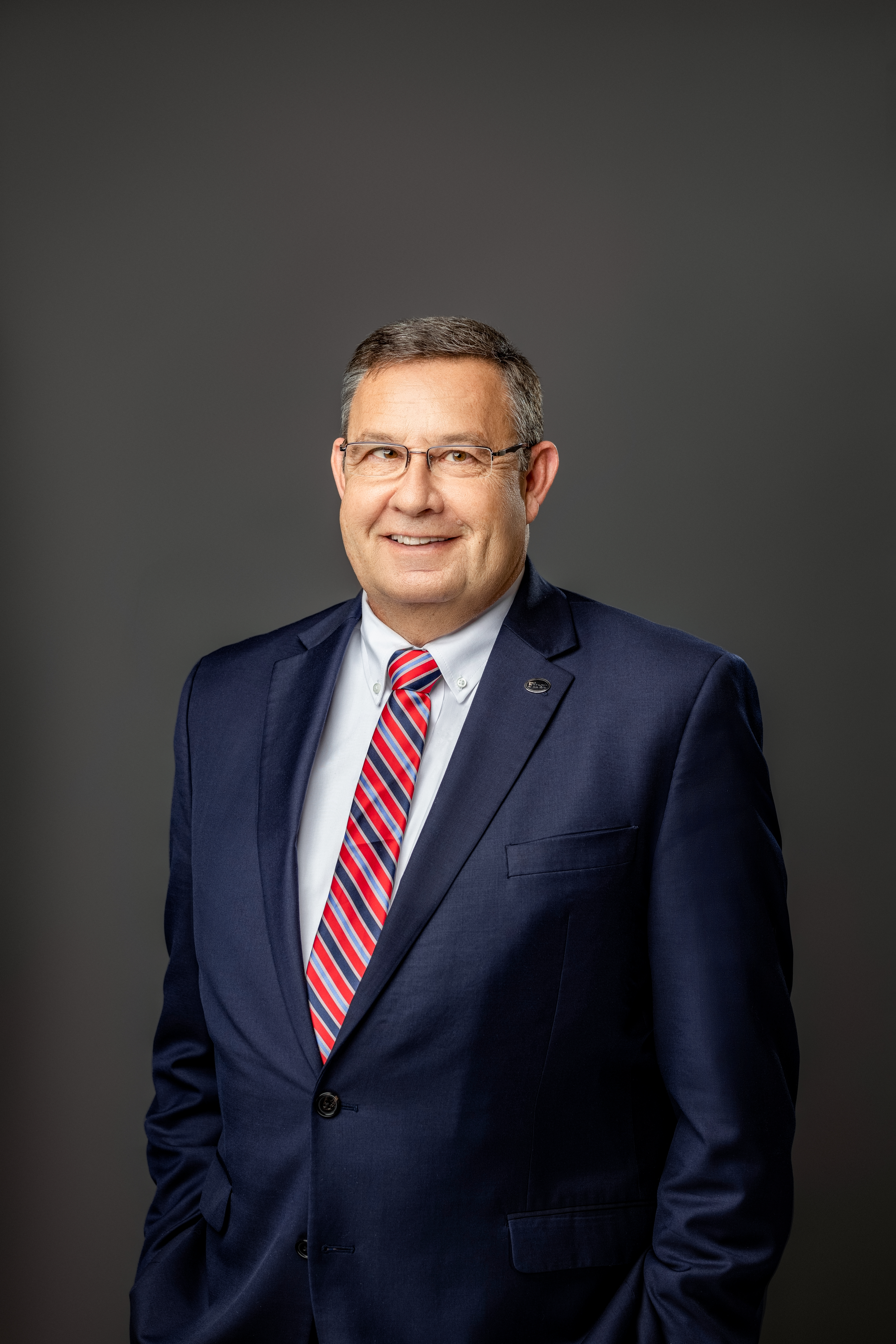 Mark Nelson in dark blue suit with striped tie