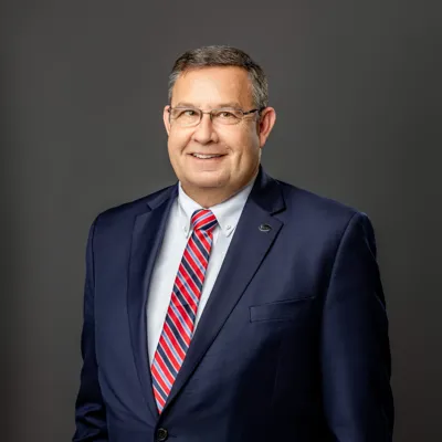 Mark Nelson in dark blue suit with striped tie