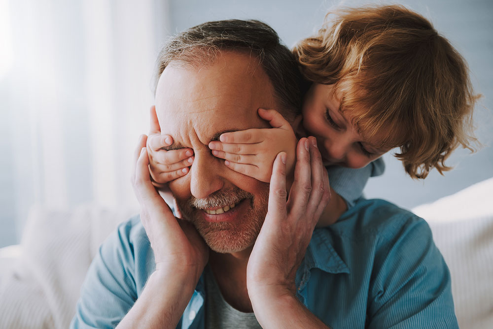 child placing hands over fathers eyes