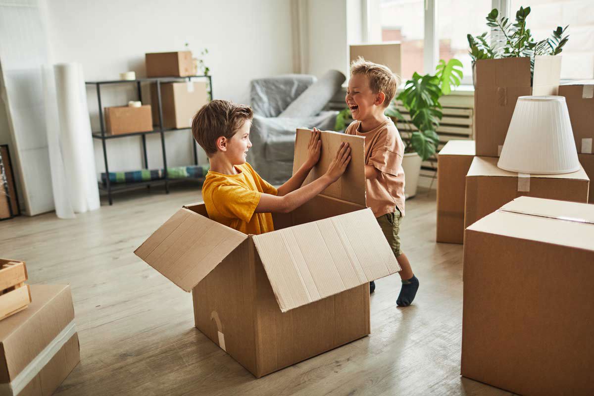 Boys Playing With Boxes In New Home