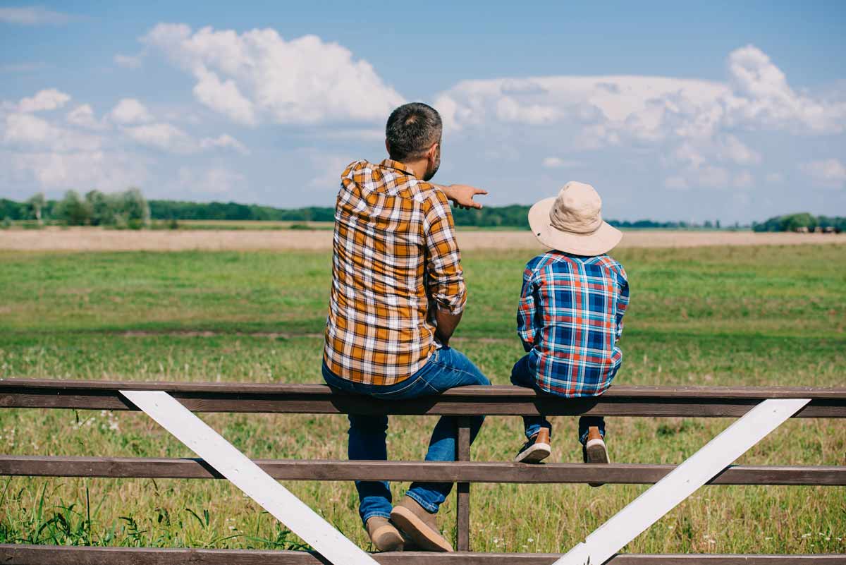 Man Pointing On Fence With Young Son