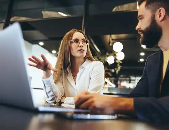 Blonde Woman And Bearded Man Talking Near Laptop