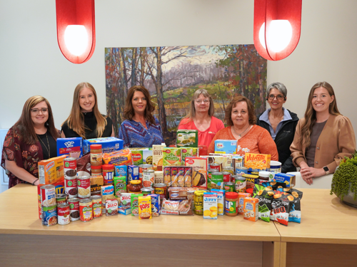 First Bank and Trust employees standing with a pile of food donations collected for Legal Food Frenzy.