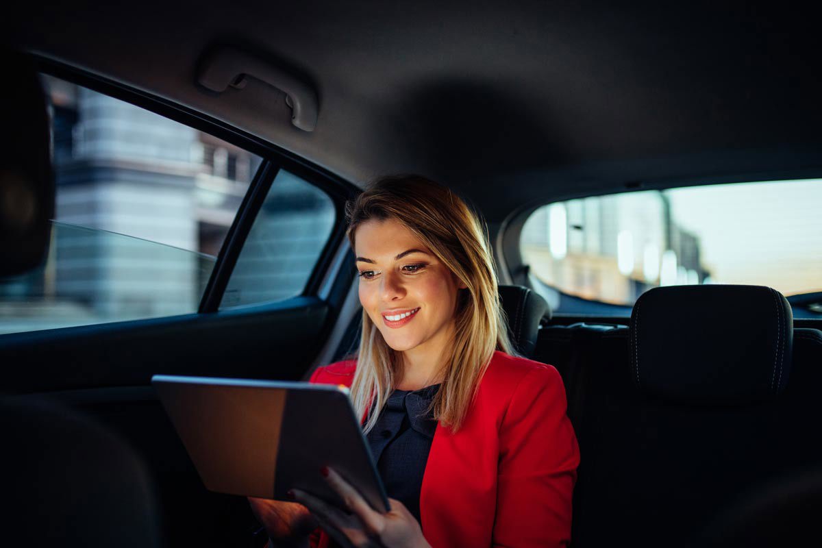 Blonde Woman Smiling At Tablet In Car