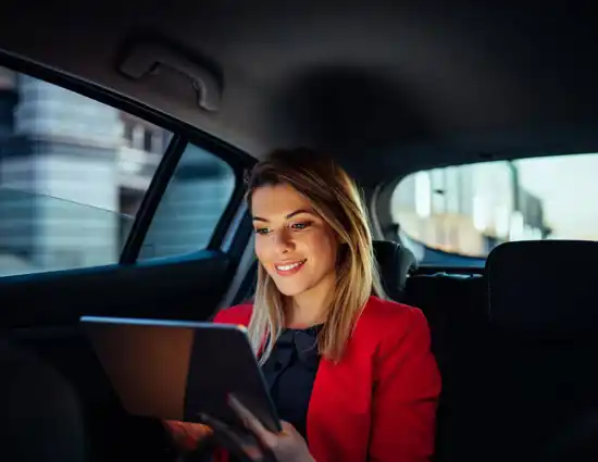 Blonde Woman Smiling At Tablet In Car