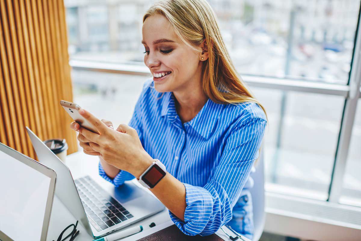 Blonde Woman In Blue Shirt Smiling At Phone