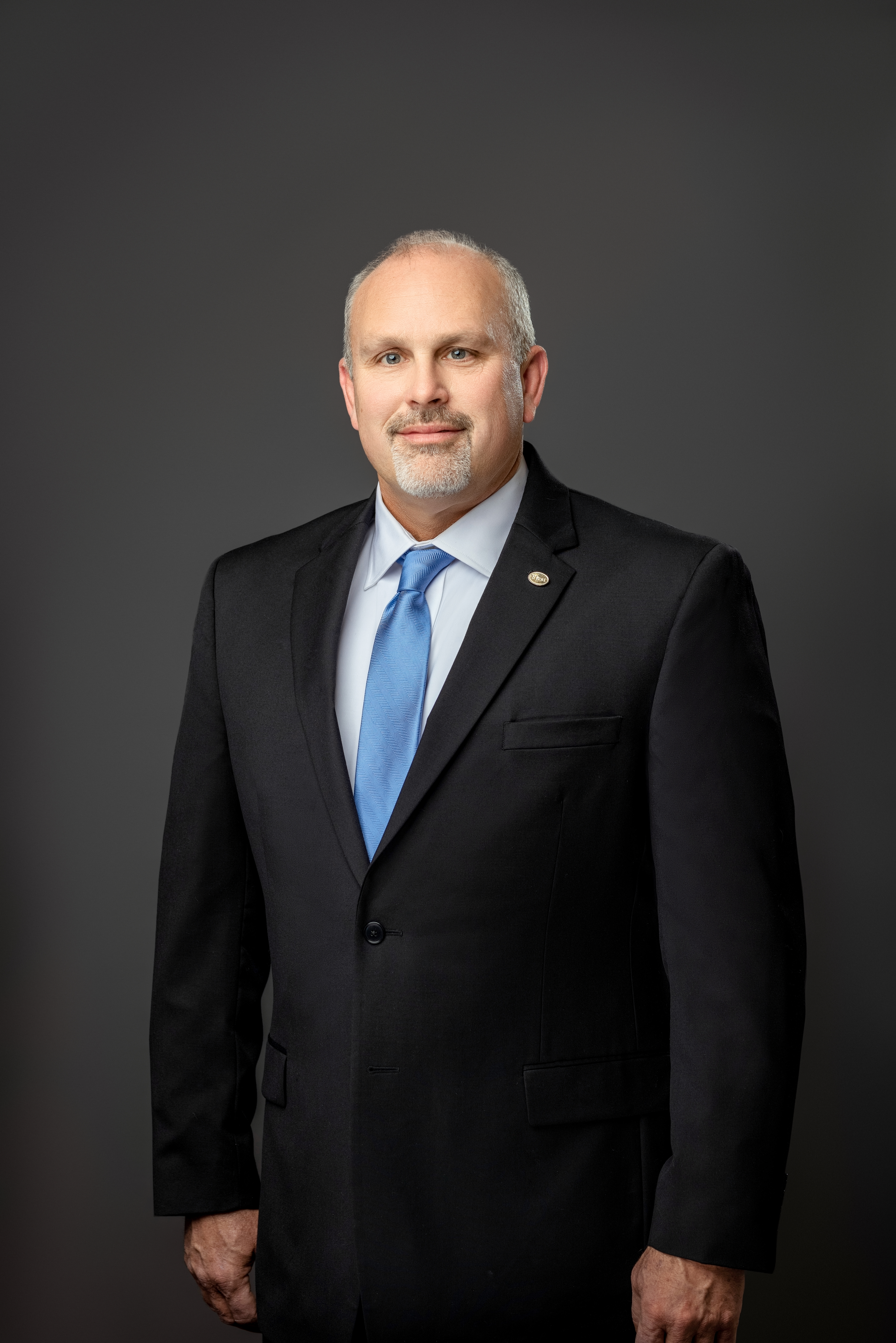 Ronald L. Barrett, II in dark black suite with blue tie