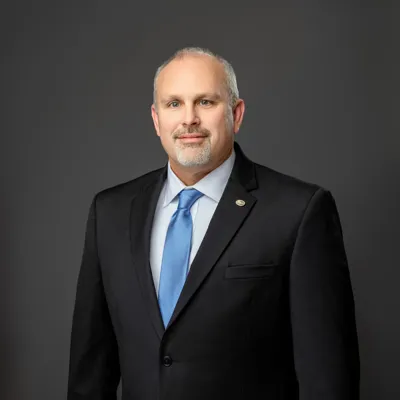 Ronald L. Barrett, II in dark black suite with blue tie