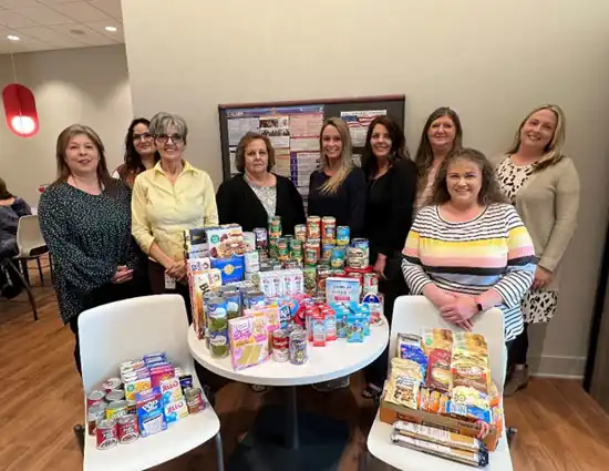 A Group Of Ladies Around The Canned Food Drive