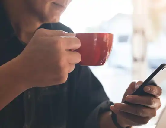 Person Holding Red Coffee Mug And Cellphone