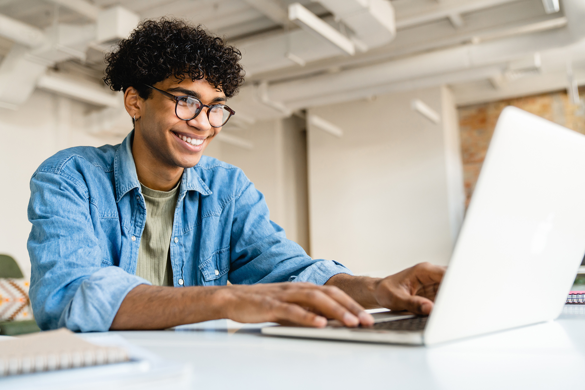 Male student sitting in front of an open laptop to refinance loan