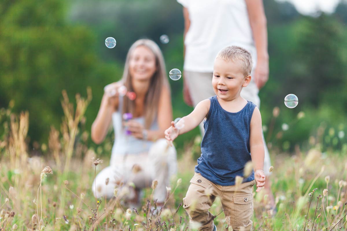 Happy Child With Family Having A Great Time Blowing Bubbles