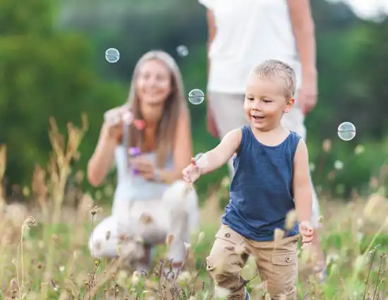 Happy Child With Family Having A Great Time Blowing Bubbles