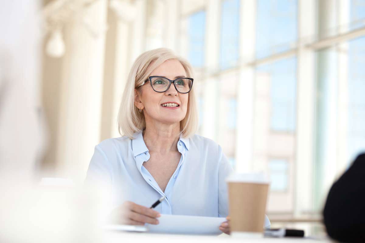 Blonde Woman With Glasses Smiling In Meeting