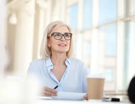 Blonde Woman With Glasses Smiling In Meeting